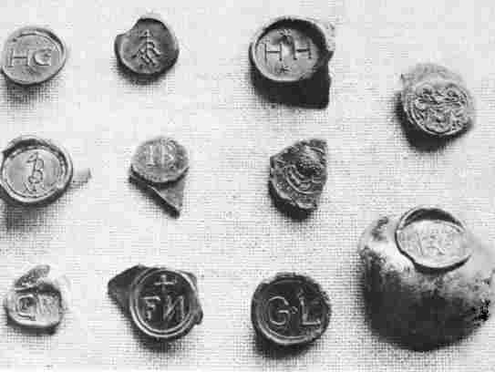 [Illustration: An assortment of glass bottle seals in the Jamestown collection. Some of the wealthy planters had their initials (or other ornamental device) stamped on the shoulders of the wine bottles which they ordered from England.]