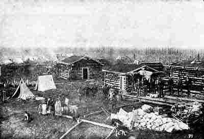 Settlement of cabins and tents; log cabin raising; several men, women, children, and dogs.